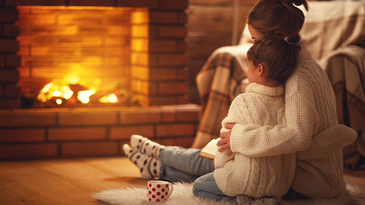 mother and daughter siting in front of fireplace